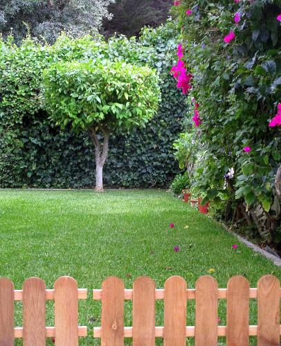 a wooden fence in front of a yard with pink flowers at Go PT - Private challet with swimming pool and garden in Parede