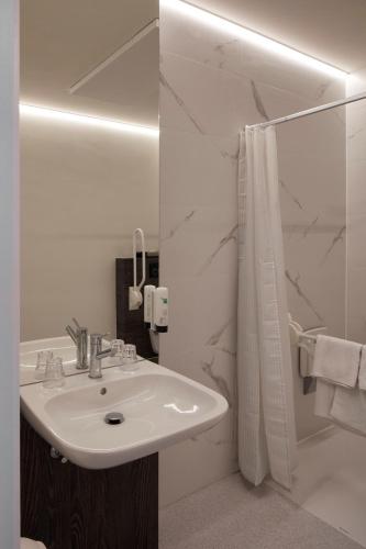 a white bathroom with a sink and a shower at Alpha Hotel and Aparthotel in Tienen
