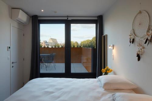 a bedroom with a bed and a view of a balcony at Alpha Hotel and Aparthotel in Tienen