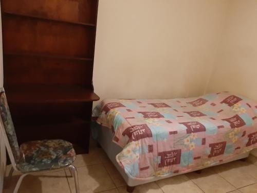 niewielka sypialnia z łóżkiem i krzesłem w obiekcie Roullas gardens w mieście Pretoria