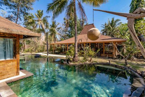 a pool in front of a house with palm trees at Kuno Villas in Gili Trawangan