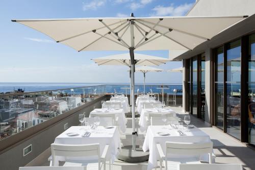 a restaurant with white tables and umbrellas on a balcony at TURIM Santa Maria Hotel in Funchal