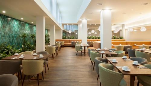 a restaurant with tables and chairs and plants at TURIM Santa Maria Hotel in Funchal