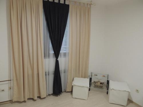 a room with a window with curtains and two stools at APARTMAN AZRA in Sarajevo