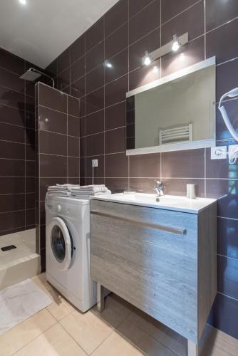 une salle de bain avec une machine à laver et un lavabo dans l'établissement Legend- Parking privé Gratuit- Terrasse privée- Wifi - Convert - Alimentec, à Bourg-en-Bresse