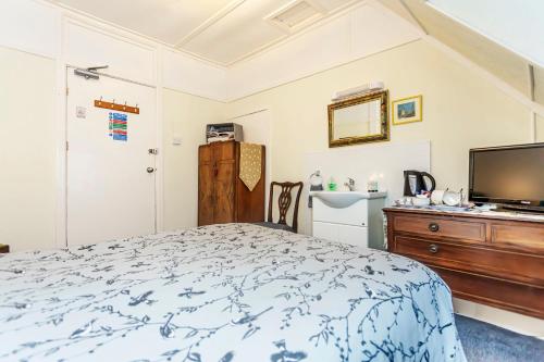 a bedroom with a bed and a flat screen tv at The Ravensbourne Hotel in Bournemouth