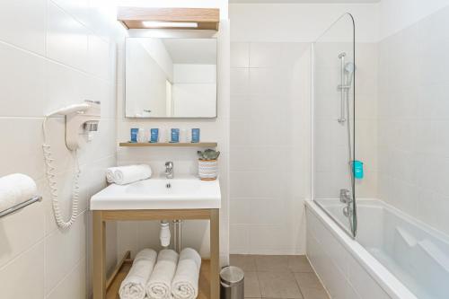 a white bathroom with a sink and a shower at Appart'City Confort Amiens Gare in Amiens