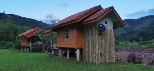 a couple of small wooden houses in a field at ต้นน้ำน่าน บ่อเกลือ in Ban Sale