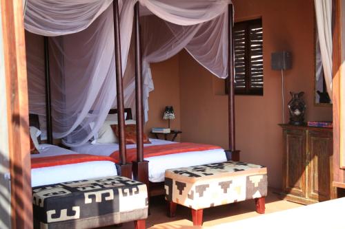 a bedroom with two beds and two ottomans at Okahirongo Elephant Lodge in Purros
