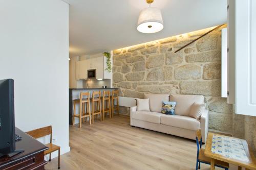 a living room with a couch and a stone wall at Estrela de Gaia Apartments in Vila Nova de Gaia