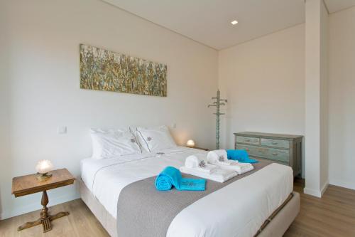 Un dormitorio con una cama blanca con toallas azules. en Estrela de Gaia Apartments, en Vila Nova de Gaia