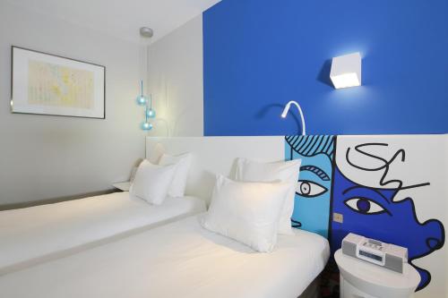a bedroom with a white bed with a blue wall at Hotel Napoléon in Menton