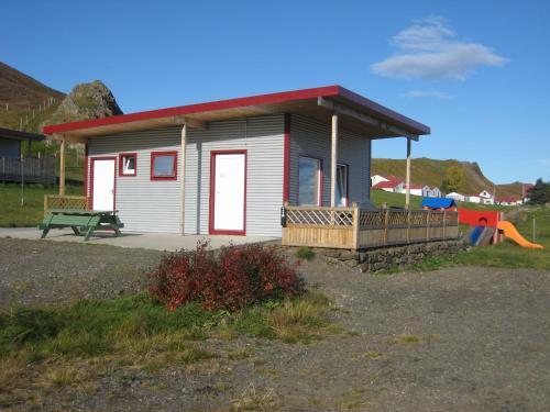 a small house with a porch and a playground at Ásbrandsstadir Cottages in Vopnafjörður