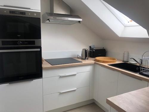 une cuisine avec des armoires blanches, un évier et une fenêtre dans l'établissement Charme en centre ville, tout équipé, local vélos, à Angers