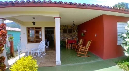 a house with a red wall and chairs on a patio at Casa Tania Fernandez in Viñales