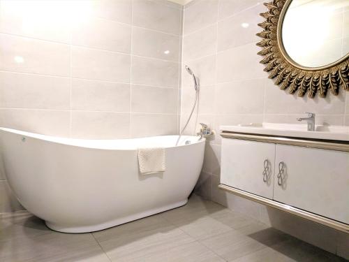 a white bathroom with a tub and a sink at Robinsons Apartments at Times Square KL in Kuala Lumpur