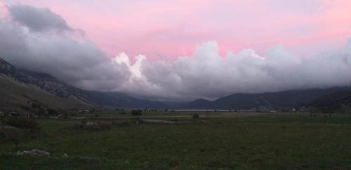 a field with a cloudy sky with mountains in the background at Chalet Vista Lago in San Gregorio