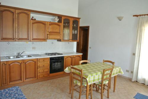 una cocina con armarios de madera y una mesa con sillas. en Case Vacanza Fenicotteri, en San Teodoro
