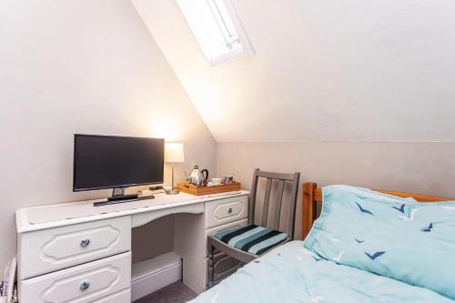 a bedroom with a desk with a tv and a bed at The Ravensbourne Hotel in Bournemouth
