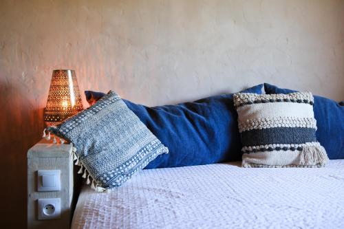 a bed with blue pillows and a lamp on it at Le Mas Des Brunes in Saint-Laurent-dʼAigouze