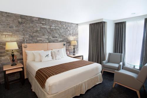 a hotel room with a large bed and a chair at Hotel du Vieux Quebec in Quebec City