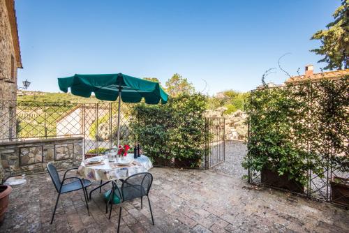a patio with a table and chairs and an umbrella at Agriturismo La Ferrozzola in Castellina in Chianti