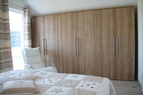 1 dormitorio con armarios de madera, 1 cama y 1 silla en Breeger Boddenidyll en Breege