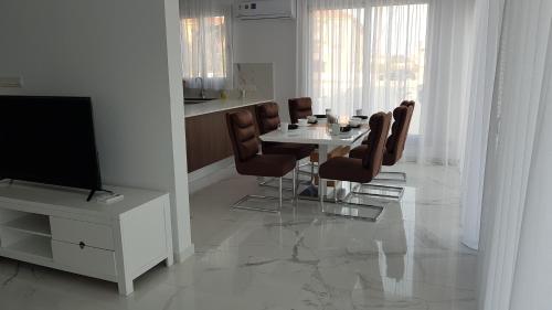 a dining room with a table and chairs and a television at Mobina Villas in Larnaka