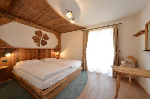 Un dormitorio con una cama grande y una ventana en Agritur Agua Biencia, en Pozza di Fassa