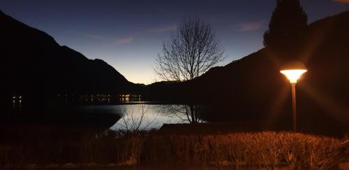 a lit street light next to a lake at night at Appartamento Chiara in Ledro