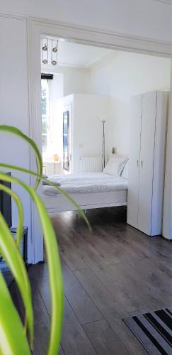 a white bedroom with a bed and a plant at Camden Habitat in London