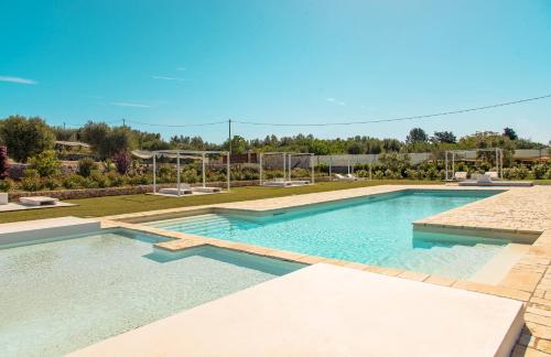 a swimming pool with blue water in a yard at Tenuta Ermes in Ostuni
