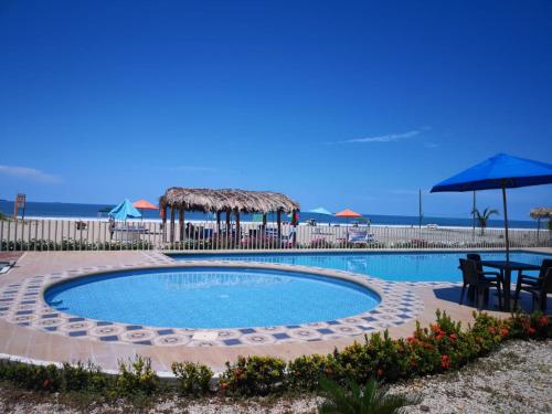 einen Pool mit einem Tisch und Sonnenschirmen in der Unterkunft Villa Altamar in Playas