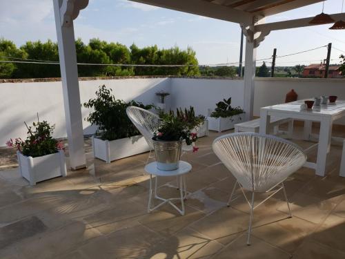 a patio with two chairs and tables and potted plants at Casa Litarà in Cutrofiano