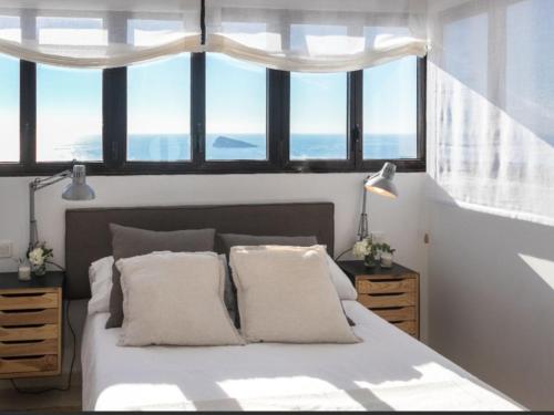 a bedroom with a large bed with windows at ATICO BENIDORM PLANTA 25 in Benidorm
