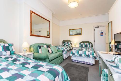 a room with two beds and a couch and a mirror at The Ravensbourne Hotel in Bournemouth