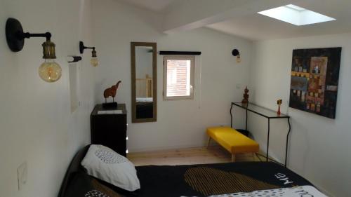 a bedroom with a bed and a yellow bench in it at Maison au pied de la cathédrale in Elne