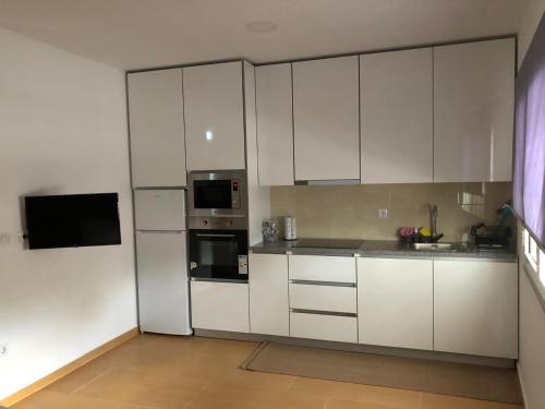 uma cozinha branca com armários e electrodomésticos brancos em Marqueses de Ferreira em Lamas de Ferreira