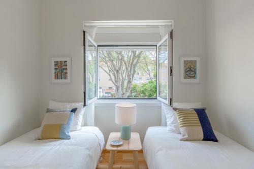 dwa łóżka w pokoju z oknem w obiekcie Sunny, Bright and Quiet Apartment, By TimeCooler w Lizbonie