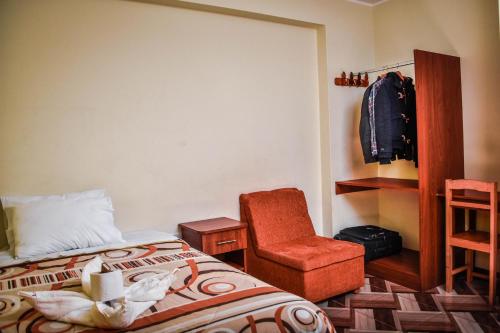a bedroom with a bed and a chair at Hostal Berlin in Jauja