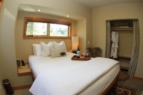 a bedroom with a large white bed with a window at Black Bear Guesthouse in Tofino