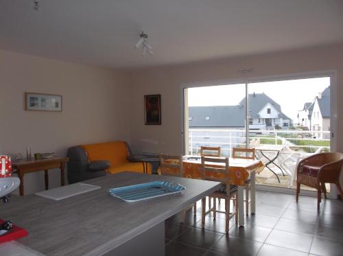 a living room with a table and chairs and a large window at villa marine 2 in Jullouville-les-Pins