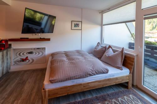 Schlafzimmer mit einem Bett, einem TV und einem Fenster in der Unterkunft Wohnung im Herzen der Turracher Höhe in Brandstätter
