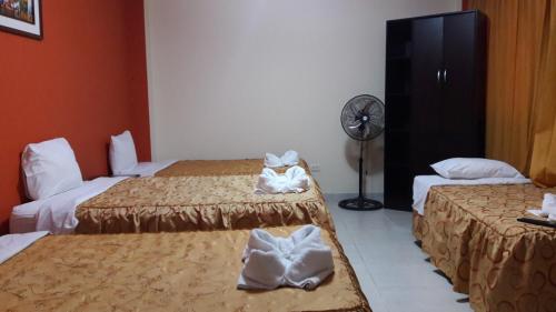 a hotel room with two beds and a fan at Madison Suite in Tacna