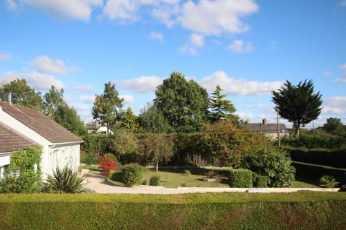 a garden with bushes and trees and a house at La Roseraie in Yvetot Bocage