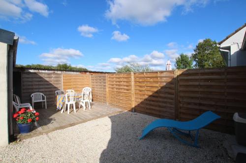 a backyard with a wooden fence and tables and chairs at La Roseraie in Yvetot Bocage