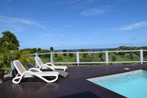 una terraza con 2 tumbonas y una piscina en Bungalow la paillote en Le François