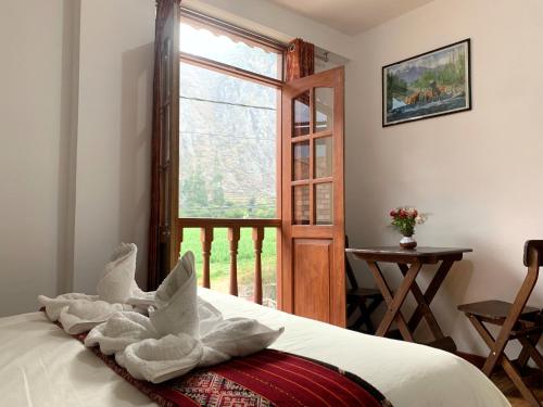 Un dormitorio con una cama con toallas y una ventana en Inka Khawarina Tambo Lodge, en Ollantaytambo