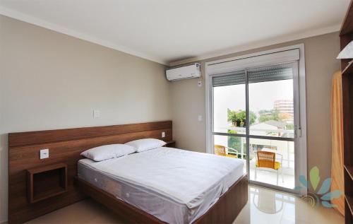 a bedroom with a bed and a large window at Residencial Bela Morada in Torres