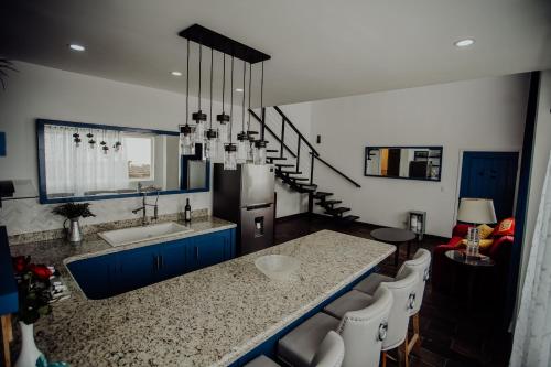 a kitchen with a sink and a counter with chairs at Trojan House in Ensenada